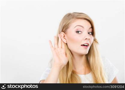 Gossip,rumors, whisper, hearing concept. Young blonde Woman putting hand ear to hear better. Studio shot on white background.. Woman putting hand ear to hear better
