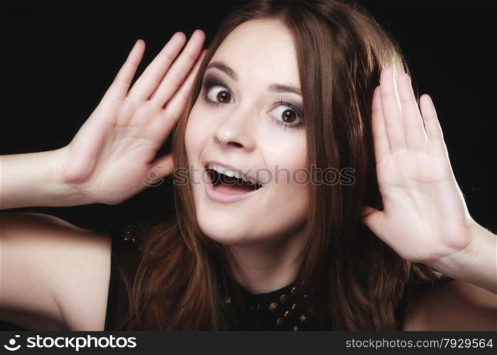Gossip scandal or secrets. Young woman teen girl with hands to ear listening on black