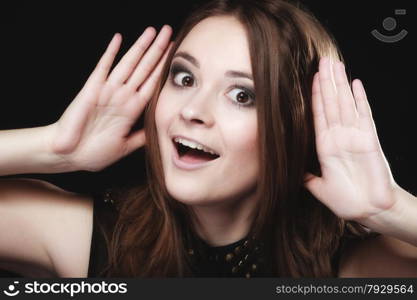 Gossip scandal or secrets. Young woman teen girl with hands to ear listening on black