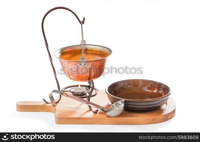 Goulash soup in a pot with ladle and plate on white background
