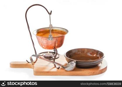 Goulash soup in a pot with ladle and plate on white background