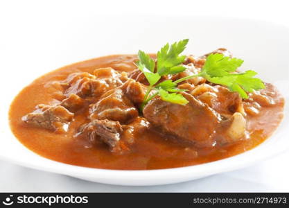 Goulash stew with parsley served in white bowl
