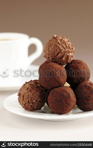 Gourmet chocolate truffles on a plate with a cup of coffee