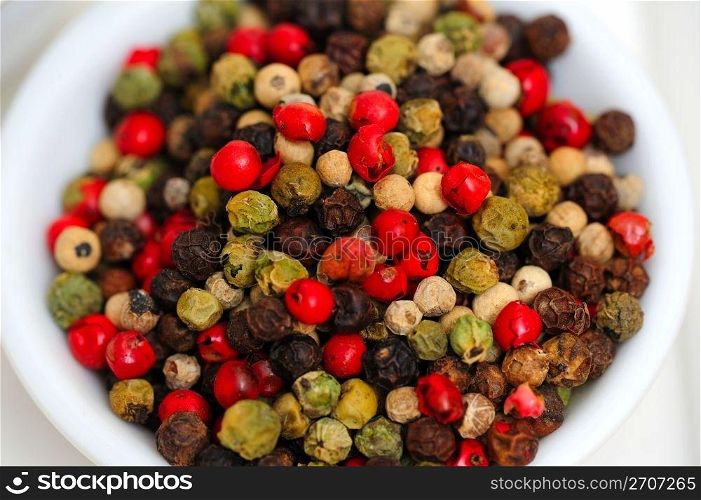 Gourmet Rainbow Peppercorns. Peppercorns in various colors of red, green and the familiar black peppercorn on white in a small bowl