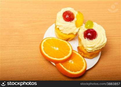 Gourmet tasty cookie cake with sweet cream and fruits as dessert food on top served with orange on plate. . Gourmet cream cake cookie and orange on plate