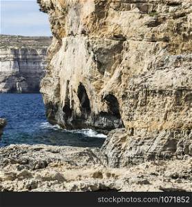 Gozo is a small island of the Maltese archipelago in the Mediterranean Sea. Rugged coastline delineated by sheer limestone cliffs, and dotted with deep caves