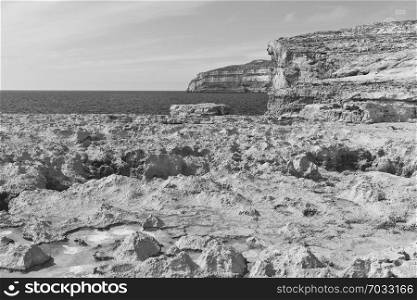 Gozo is a small island of the Maltese archipelago in the Mediterranean Sea. Rugged coastline delineated by sheer limestone cliffs, and dotted with deep caves. Black and white picture