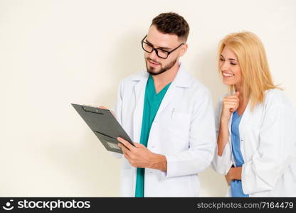GP doctor looks at data in documents on clipboard while discussing with surgical doctor on white background. Medical service and healthcare concept.. Doctors looking and discussing on documents paper.