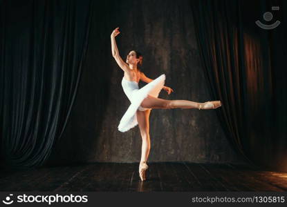 Graceful ballerina in white dress dancing in class. Ballet dancer training on the stage