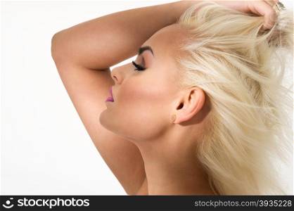 Graceful gorgeous blond woman standing with her arm raised above her head with her eyes closed and a blissful serene expression, close up profile view head shot over white