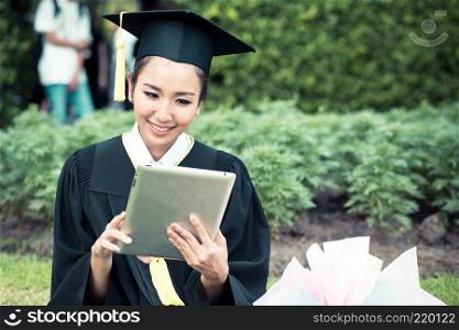Graduate playing tablet in her hand feeling relaxing and so happiness in commencement day and search job new.