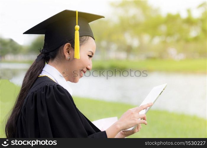 Graduate playing tablet in her hand feeling relaxing and so happiness in Commencement day