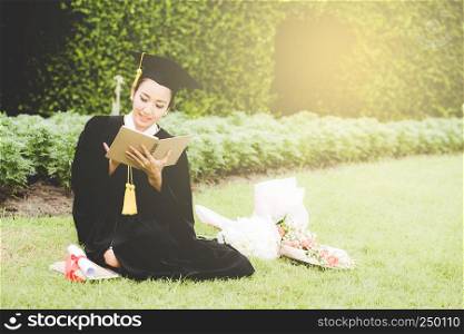 Graduate reading diary, notebook in her hand feeling relaxing and so happiness in commencement day