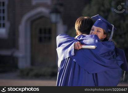 Graduates Hugging And Holding Diplomas