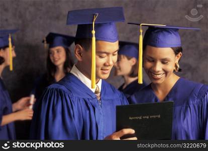 Graduates Looking At Diploma And Smiling