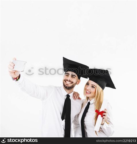 graduating couple mortarboards taking selfie