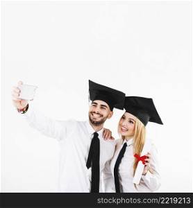 graduating couple mortarboards taking selfie