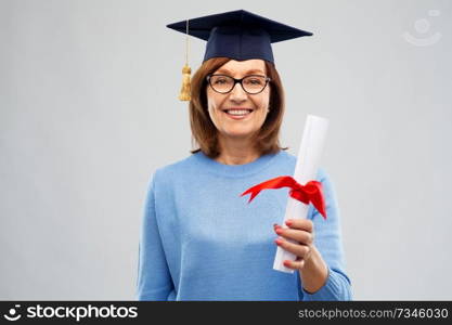 graduation, education and old people concept - happy senior graduate student woman in mortar board with diploma laughing over grey background. happy senior graduate student woman with diploma