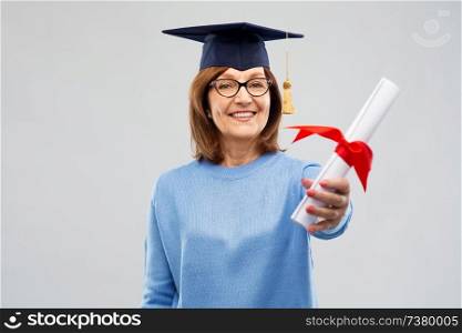 graduation, education and old people concept - happy senior graduate student woman in mortar board with diploma laughing over grey background. happy senior graduate student woman with diploma