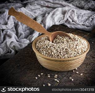 grain of wheat in a wooden bowl on a brown table, top view. grain of wheat in a wooden bowl on a brown table