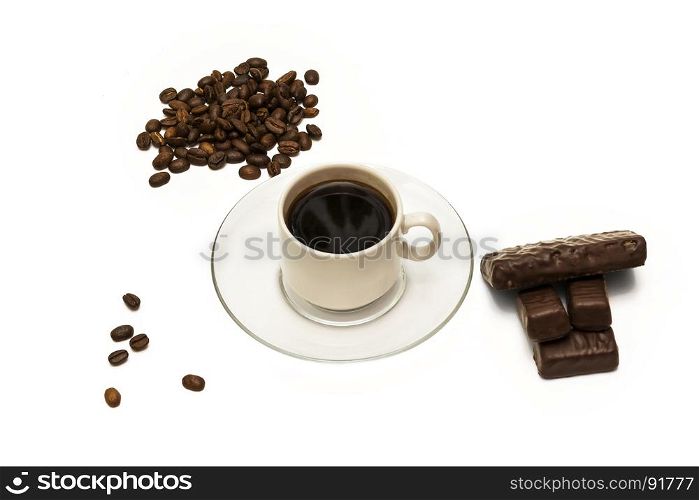Grains of coffee, a cup of coffee and chocolate candies on a white background
