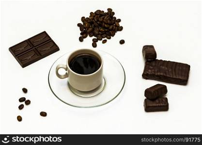 Grains of coffee, a cup of coffee with chocolate and chocolate sweets on a white background