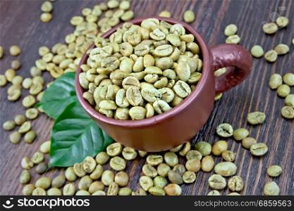 Grains of green coffee in a brown cup and on a table with leaves on a background of a dark wooden board