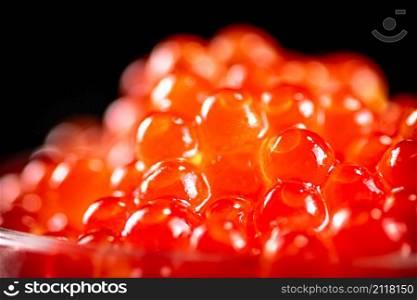 Grains of red caviar on a black background. High quality photo. Grains of red caviar on a black background.