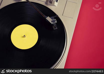 Gramophone with a vinyl record on a red table, top view and copy space,split toning for old style.