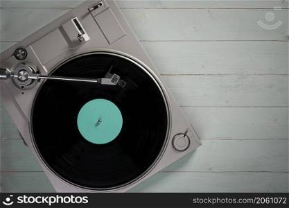 Gramophone with a vinyl record on wooden table, top view and copy space,photo desaturate and split toning for old style.