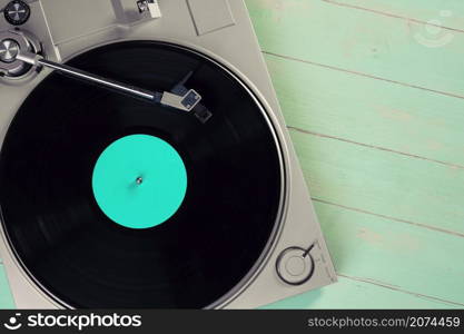 Gramophone with a vinyl record on wooden table, top view and copy space,split toning effect for old style.