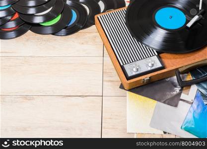 Gramophone with a vinyl records on wooden table, top view and copy space.