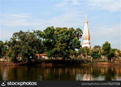 Grand ancient pagoda of Wat Phra That Phanom among big tree and lake, most sacred temple of Nakhon Phanom - Thailand
