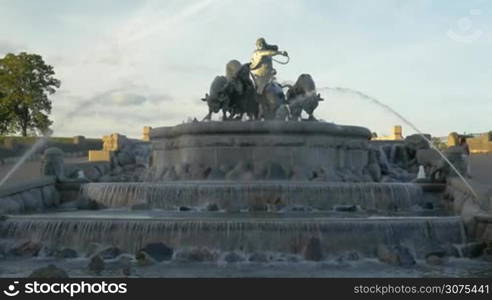 Grand Gefion Fountain in Copenhagen, Denmark. Water flowing down the steps on stones. Statue of goddess driving bulls on the top