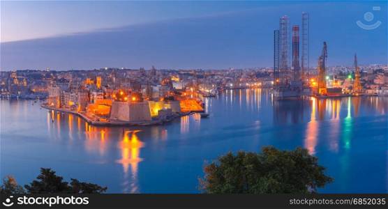 Grand harbor and Senglea from Valletta, Malta. Panoramic aerial skyline view of ancient defences of Three cities, three fortified cities of Birgu, Senglea and Cospicua and Grand Harbor with ships, as seen from Valletta during morning blue hour, Malta.