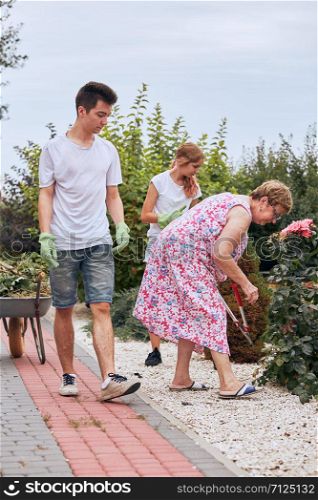 Grandchildren helping grandmother at a home garden. Candid people, real moments, authentic situations