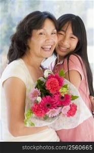 Granddaughter and grandmother holding flowers and smiling
