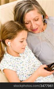 Granddaughter and grandmother listen to MP3 music headphones together smiling
