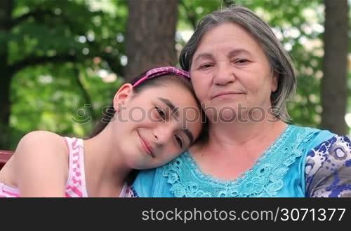 Granddaughter and grandmother smiling at camera in a park.