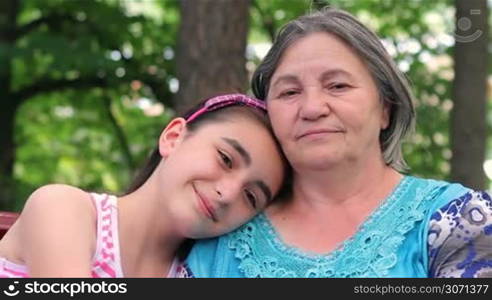 Granddaughter and grandmother smiling at camera in a park.