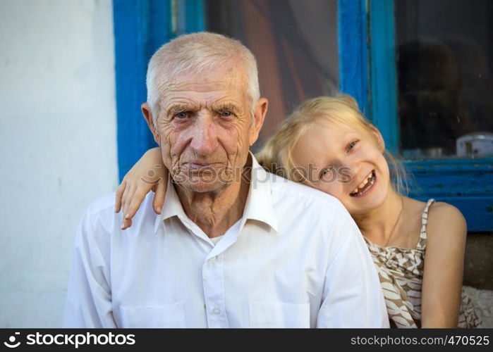 granddaughter embracing with grand parents sitting at the front of rural house