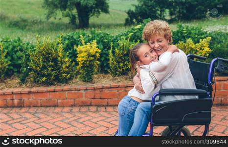Granddaughter hugging her grandmother in a wheelchair. Granddaughter hugging her grandmother