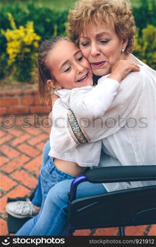 Granddaughter hugging her grandmother in a wheelchair. Granddaughter hugging her grandmother