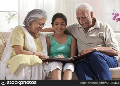 Granddaughter looking at a photo album with her grandparents