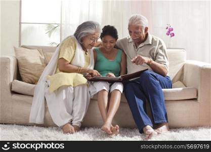 Granddaughter looking at a photo album with her grandparents