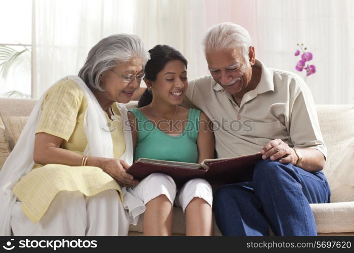 Granddaughter looking at a photo album with her grandparents