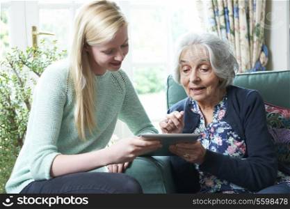 Granddaughter Showing Grandmother How To Use Digital Tablet
