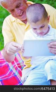 grandfather and child in park using tablet computer. grandfather and child in park using tablet