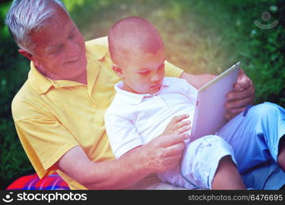 grandfather and child in park using tablet computer. grandfather and child in park using tablet