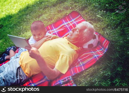 grandfather and child using tablet computer in park. grandfather and child in park using tablet